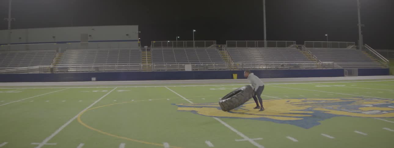 A man is exercising on the football field at night