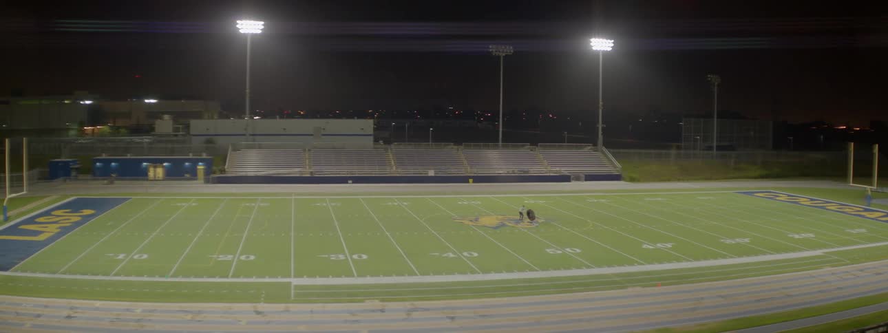 A man is training by flipping a tire on a football field