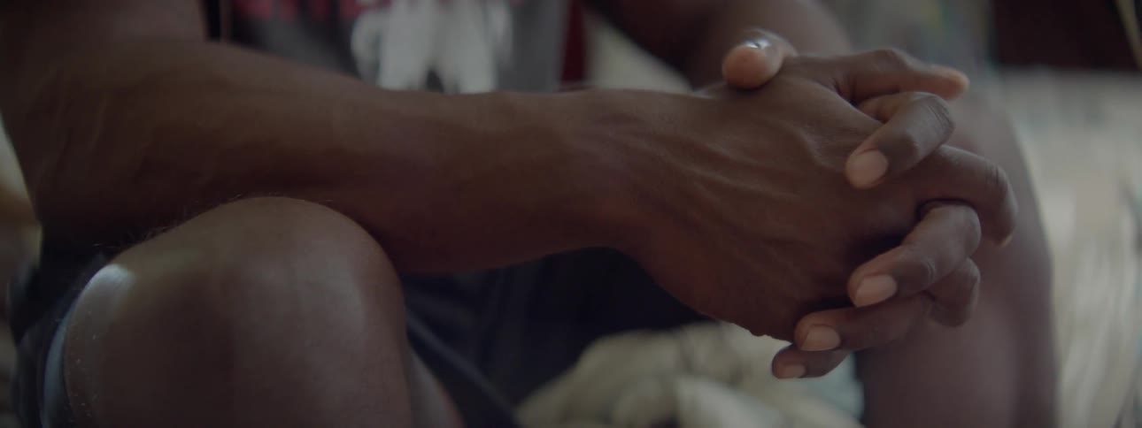 A man sits with his arms against his legs