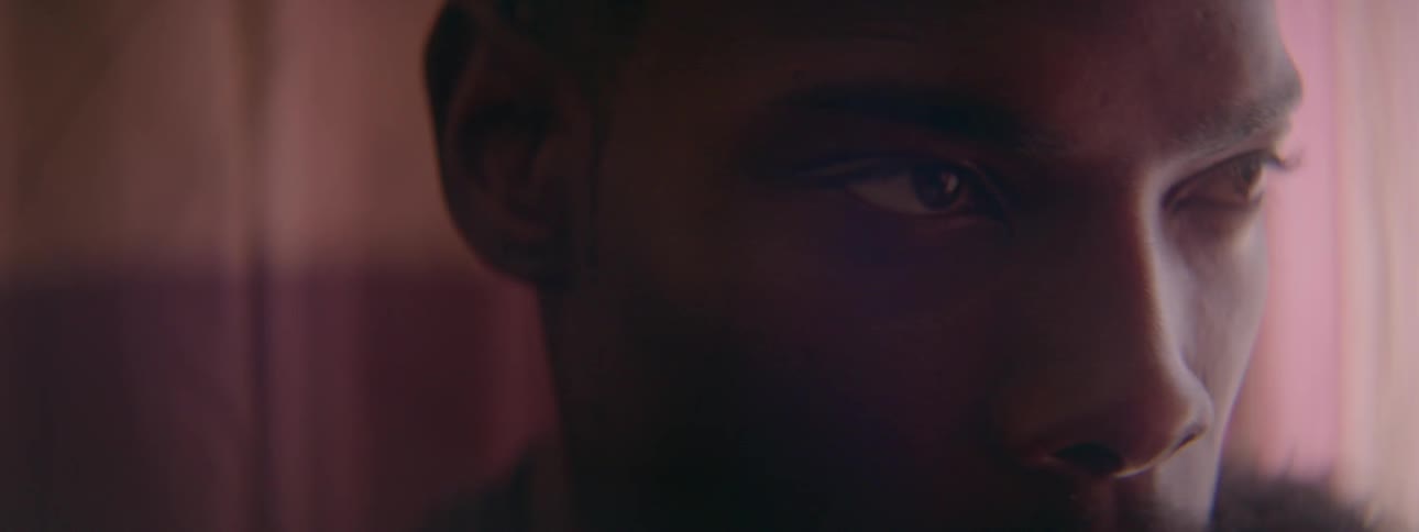 A black man nods in a red lit room