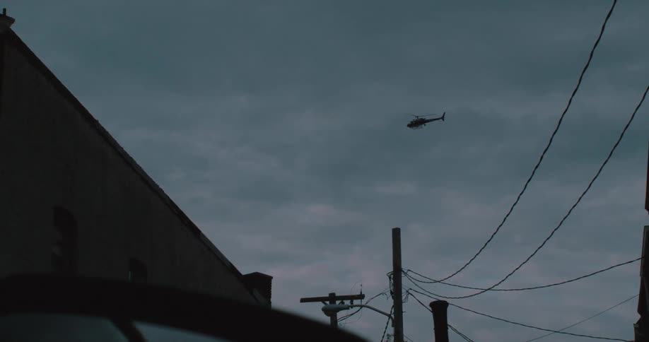 A helicopter flies over a building in slow motion