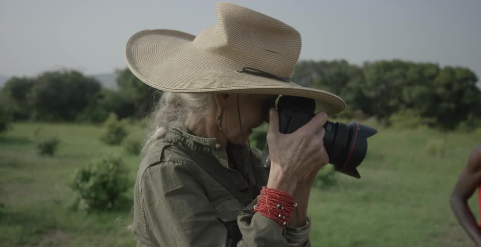 Woman wearing a large hat takes a photo with her camera