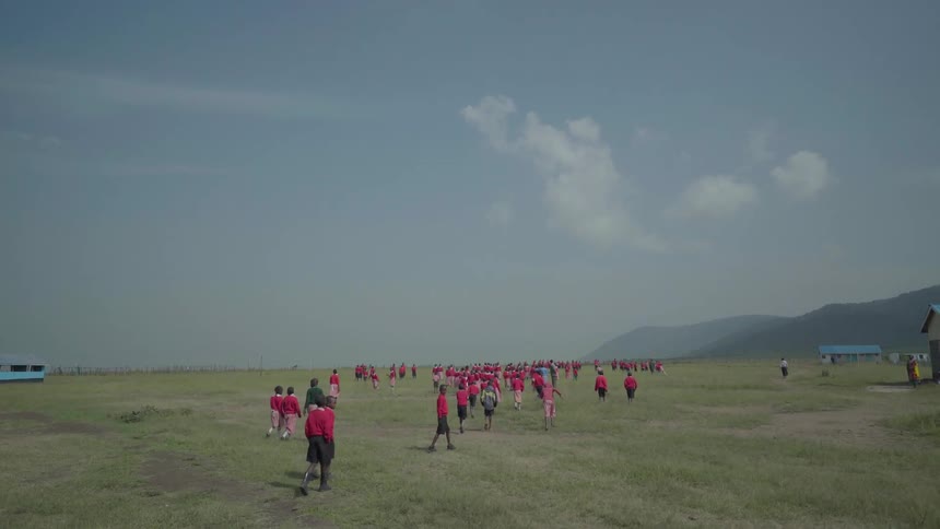 Students in school uniforms walk out onto a grassy field
