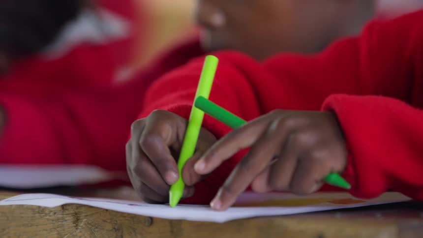 Children coloring with green and yellow crayons