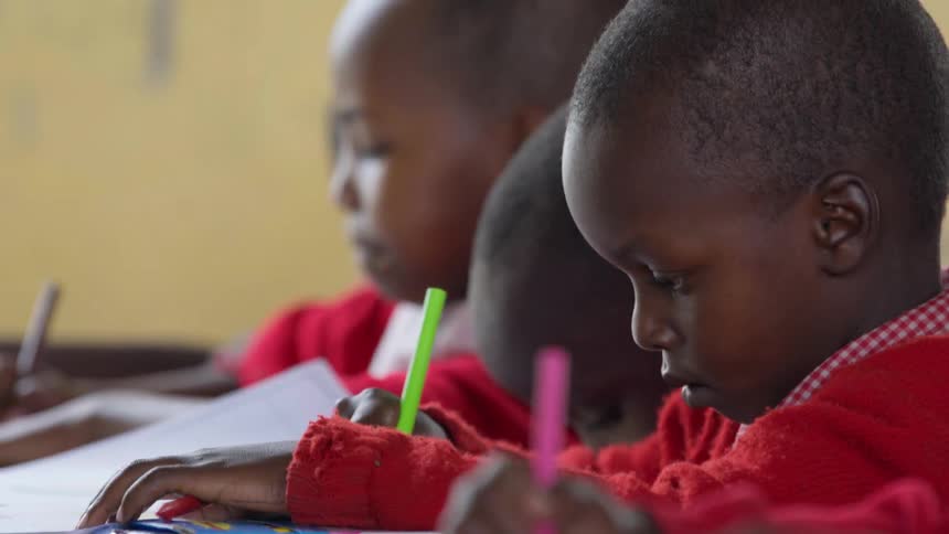 Students draw and write on paper with colored markers