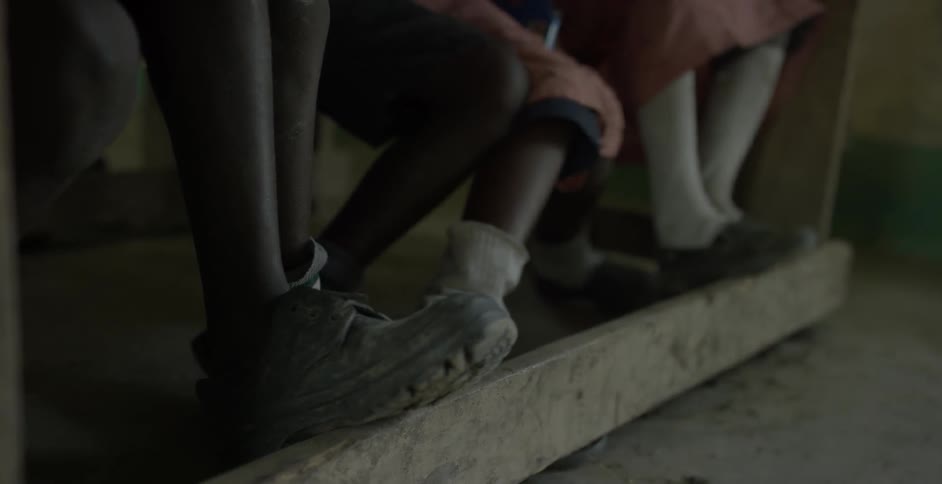 Children rest their feet on a board as they sit in a room