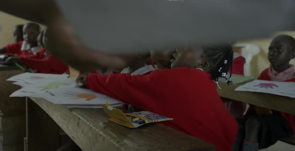 A teacher hands out papers to students in a classroom