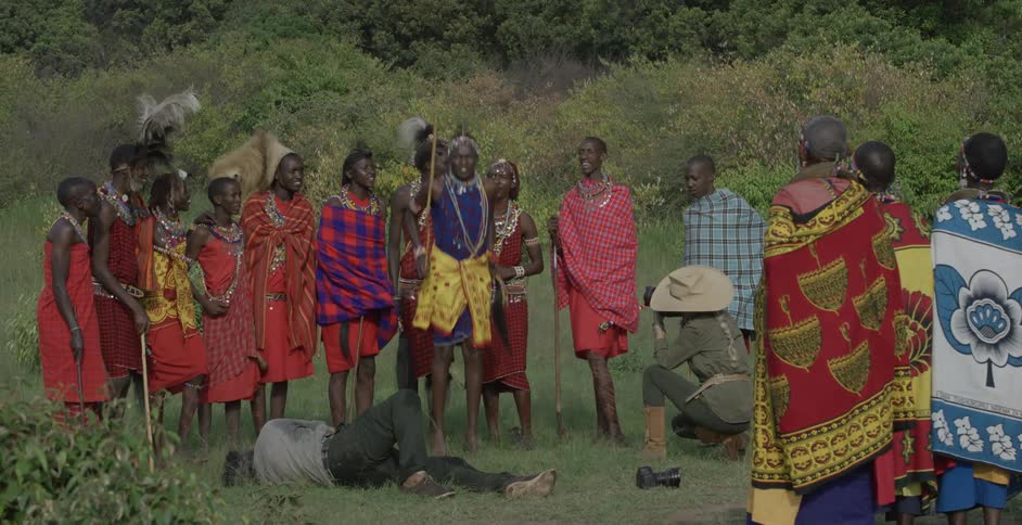 A man lays down taking photographs as a maasai jumps
