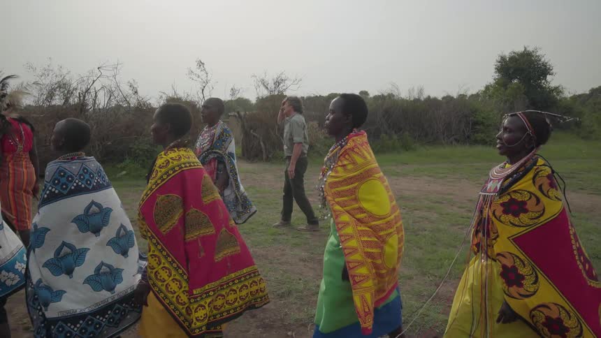A group of maasai women dance through a field