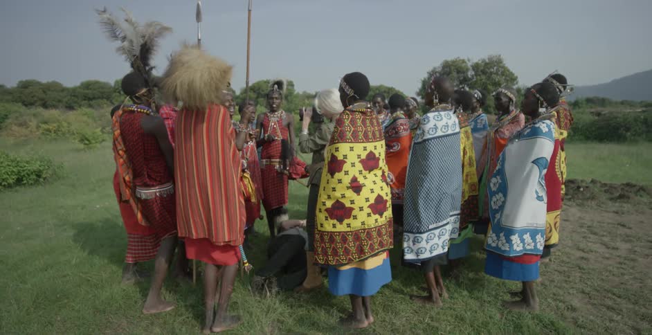 A group of maasai stand huddled together leaning forward