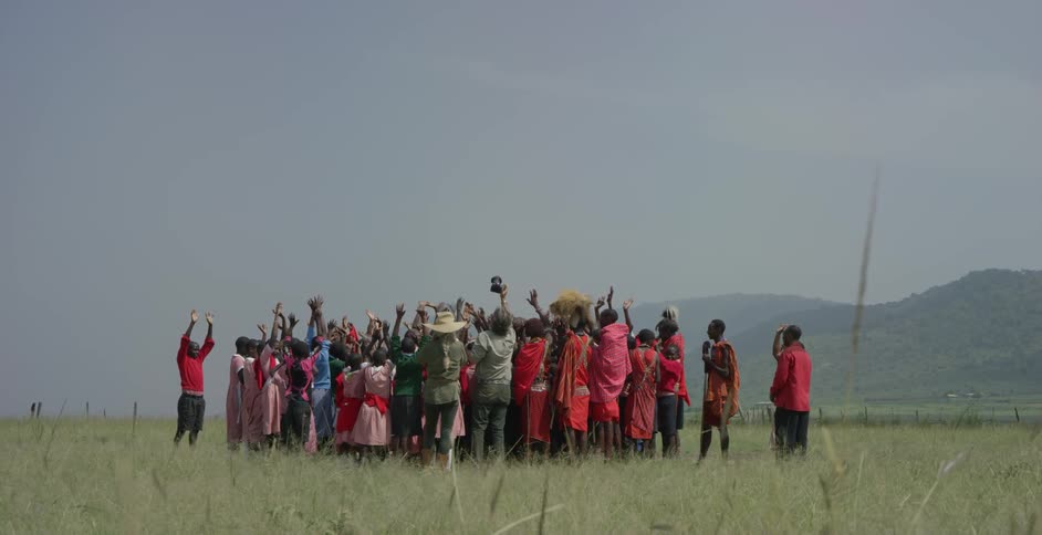 A group of maasai and photographers stand in a grassy field