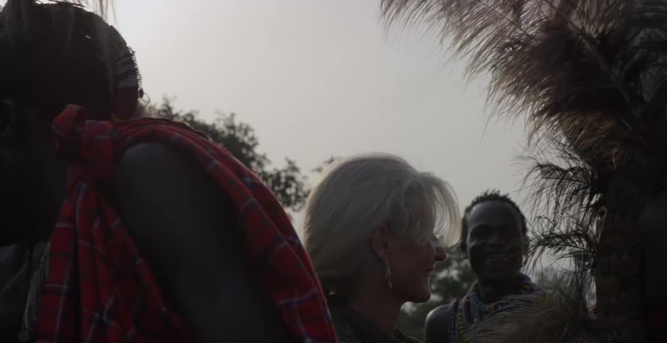 A man laughs and smiles as he shakes hands with maasai people