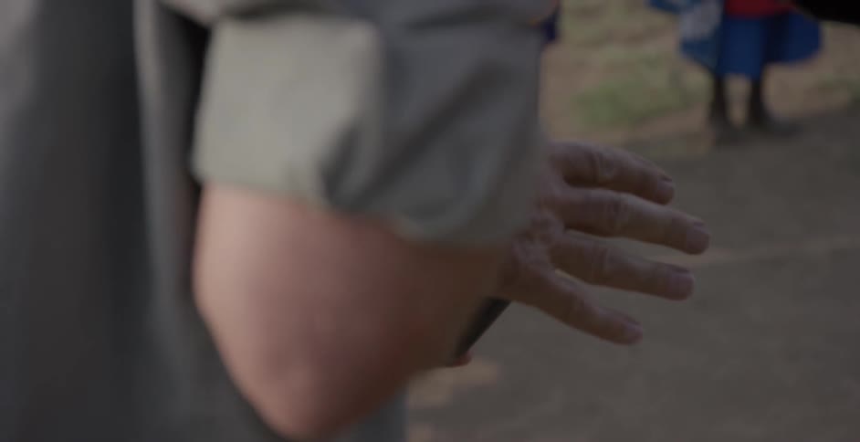 A man uses his shirt to clean the camera screen while outside