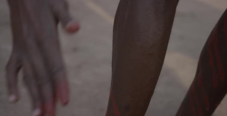 Maasai rubs red paint on their bare legs