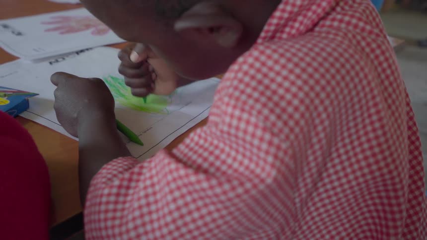 Child coloring a picture while sitting at his desk in school