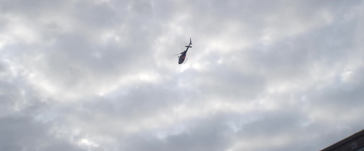 A helicopter flies in the cloud covered sky