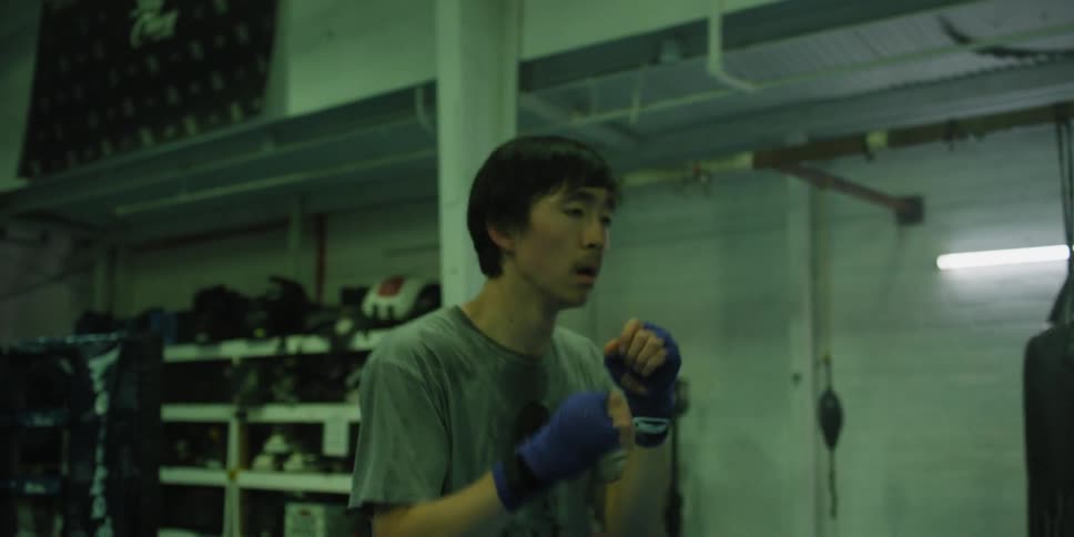 An asian man is shadow boxing in the gym