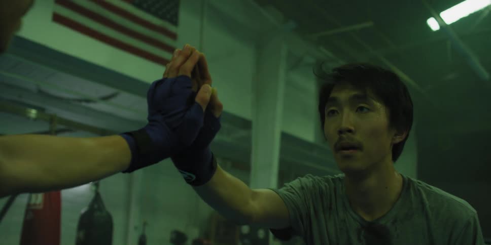 A man in a gym breathes heavy as he leans against a mirror