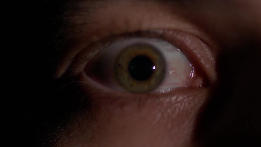 A person's eye widens as light flashes on it