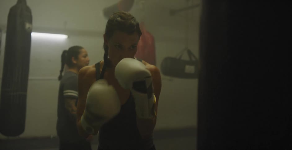 A female fighter punches a bag in a gym