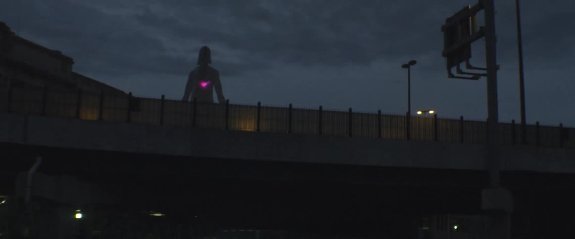 Passing under a bridge past a statue with a glowing heart