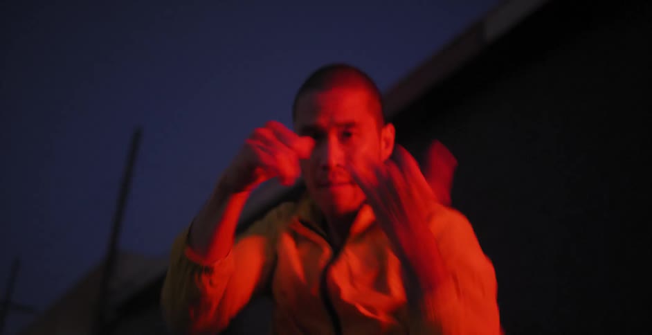 A man is shadow boxing outside at night