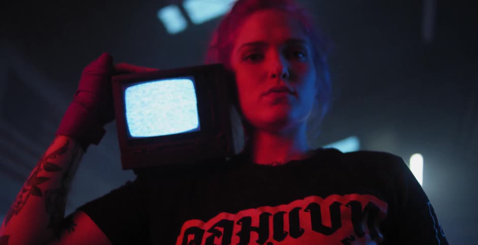 A woman is holding a small television on her shoulder