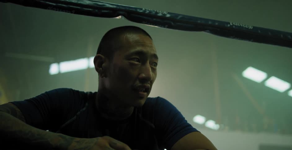 A man is leaning against the ropes in a boxing ring talking to someone
