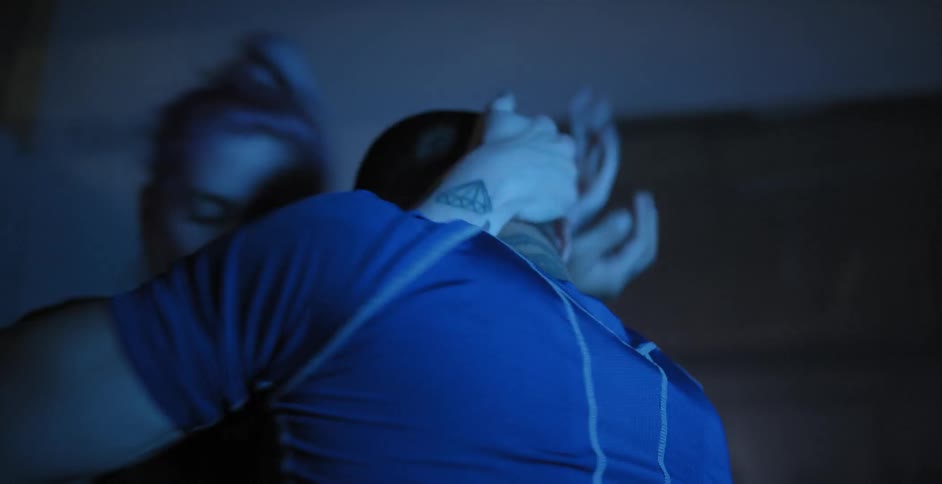 A man and woman are grappling in a gym