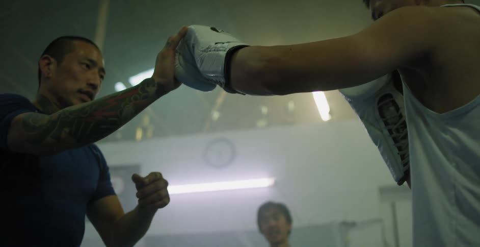 A man is teaching a group of men how to kick-box