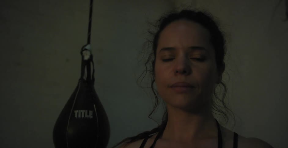 A woman is standing next to a punching bag looking at the camera