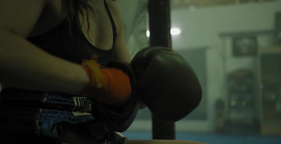 A female fighter is putting on her boxing gloves
