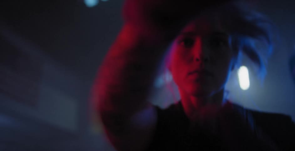 A woman is kick boxing in a dimly lit gym