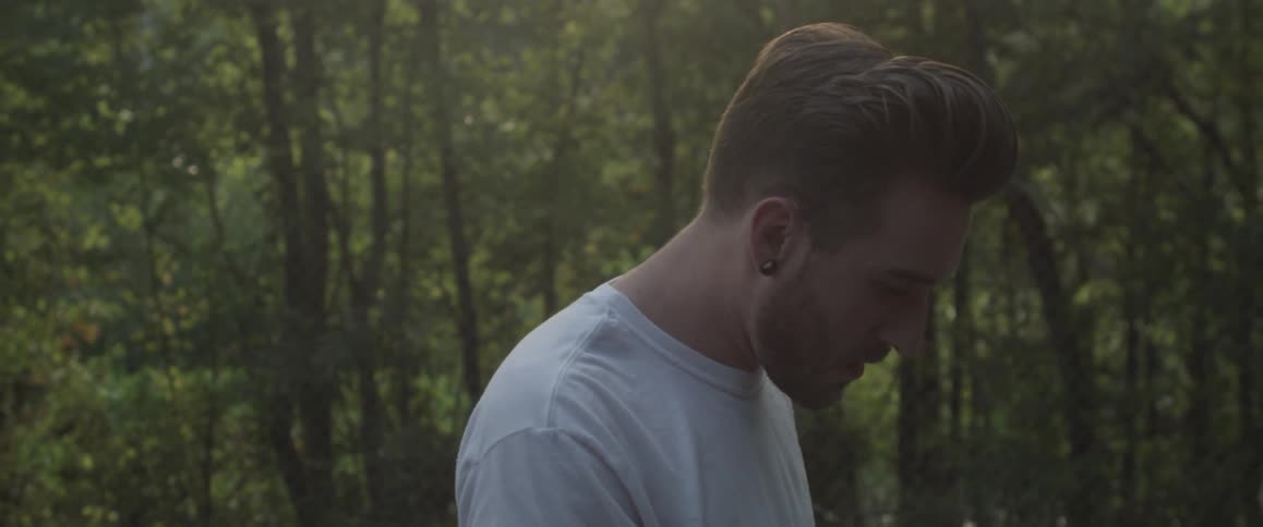 Man smokes a cigarette near trees