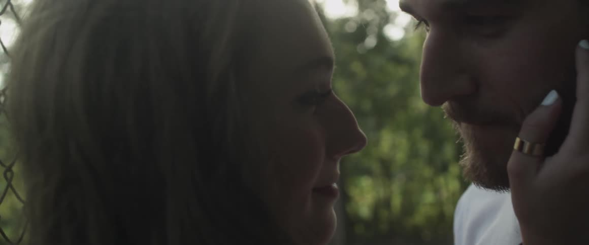 A couple stand face to face touching each other