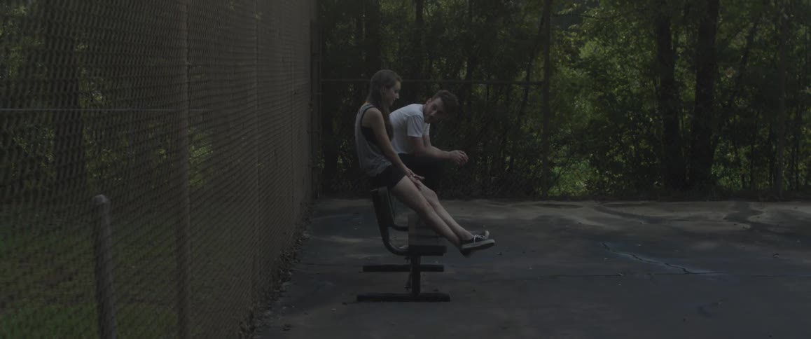 A man and woman are sitting on a park bench together