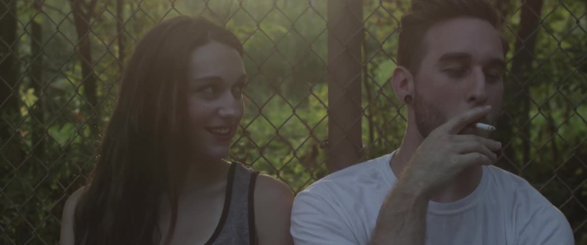 A man is smoking a cigarette next to a woman