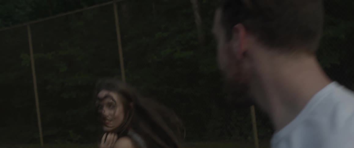 Woman smiling at man as he playfully chases her outside