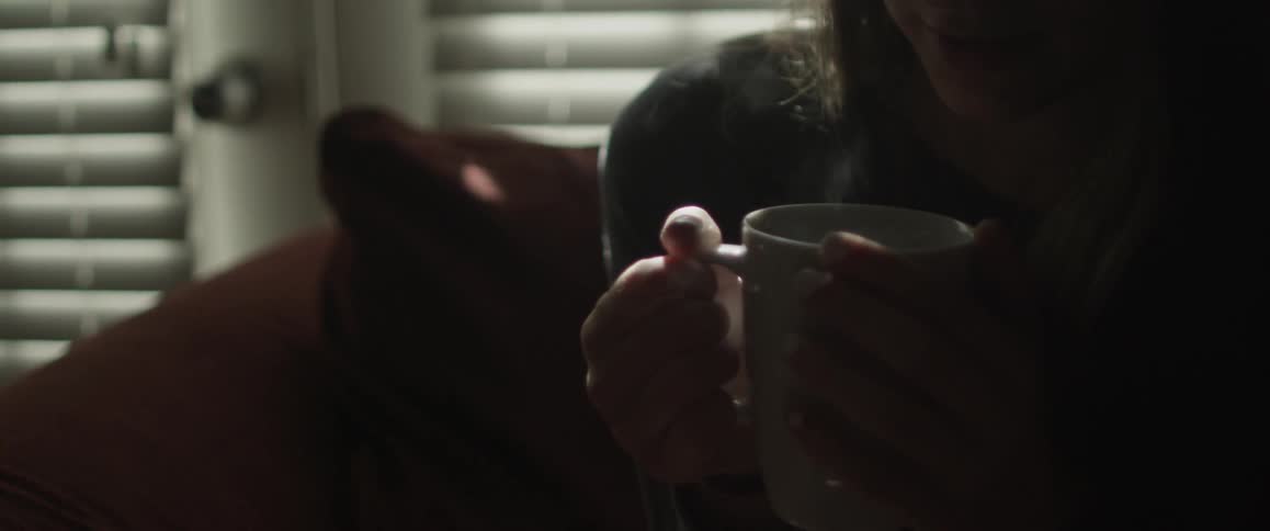 A woman is holding a cup of tea between her hands