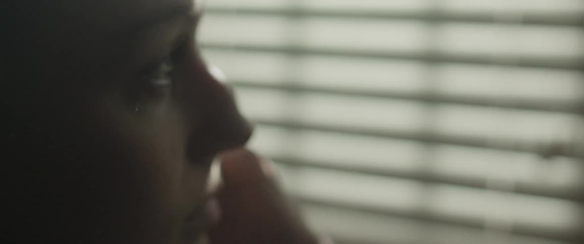 Woman looks out window as sunlight streams in
