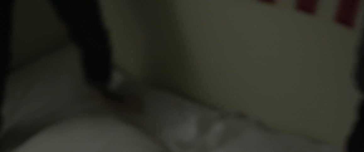 Two people jump on a bed