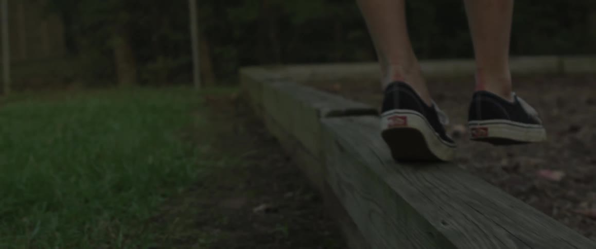 A woman is walking on top of a wooden wall
