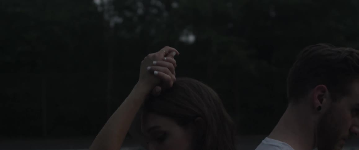 A man and woman stand back to back outside on a tennis court