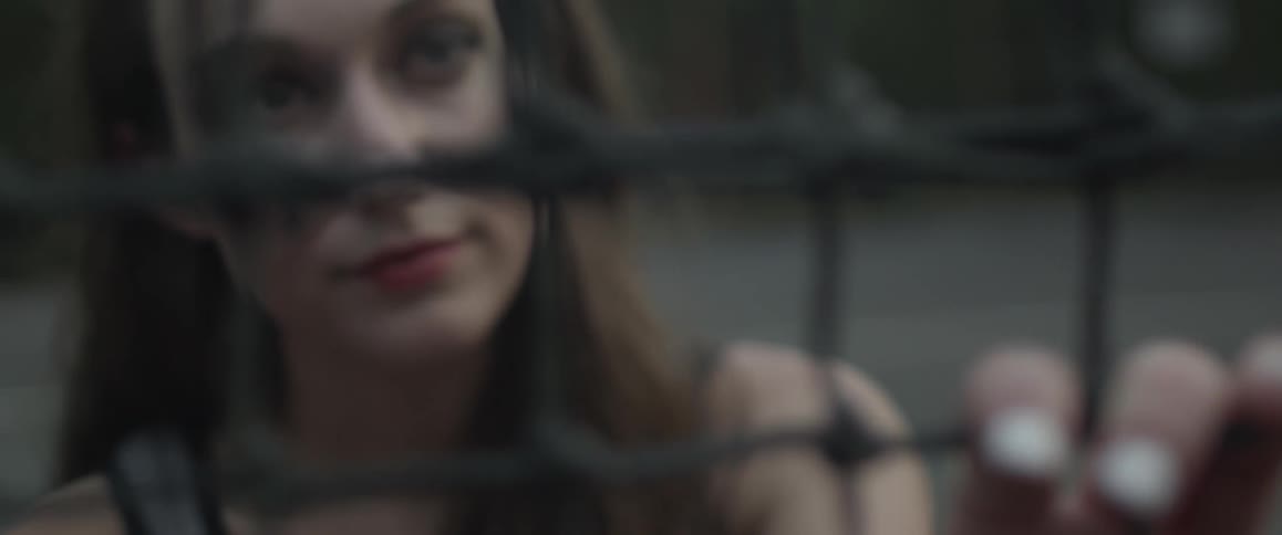 A woman puts her fingers through netting while standing outside