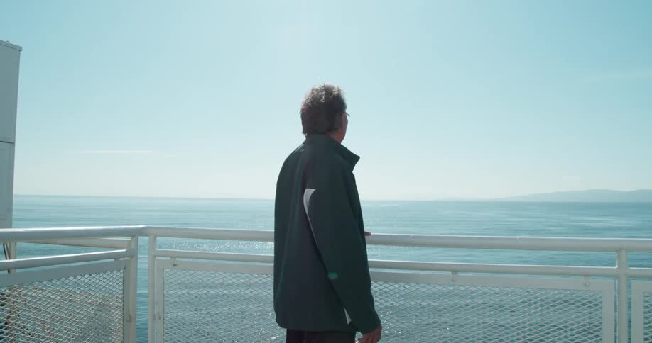 A man is looking out over the ocean while standing on a peer