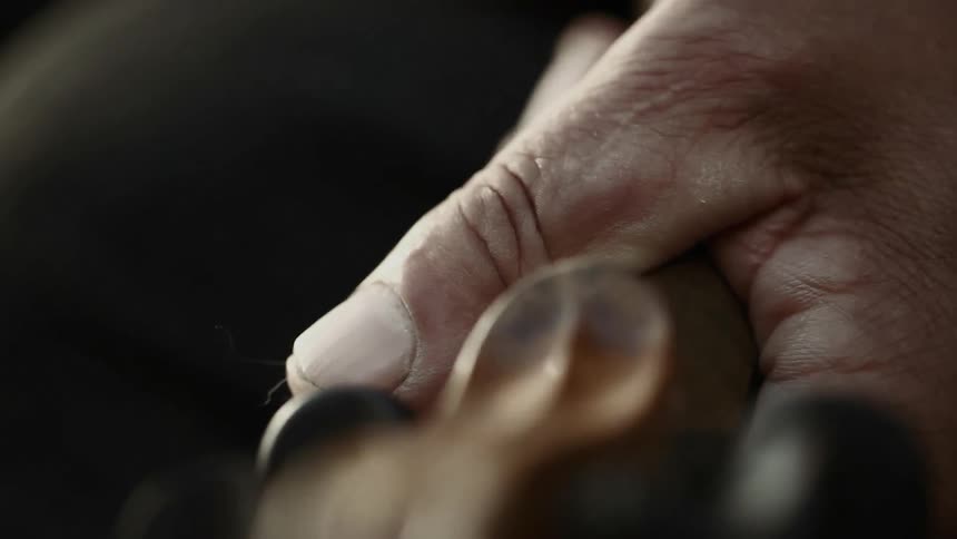 A hand holds the head of a violin