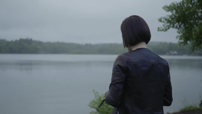 A man talks as she stand on the shore of a lake on a cloudy day