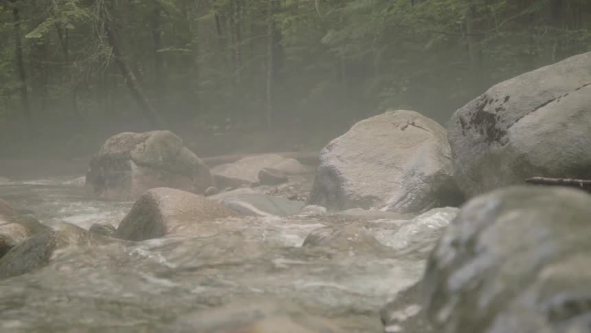 Mist hangs in the air above a fast flowing stream