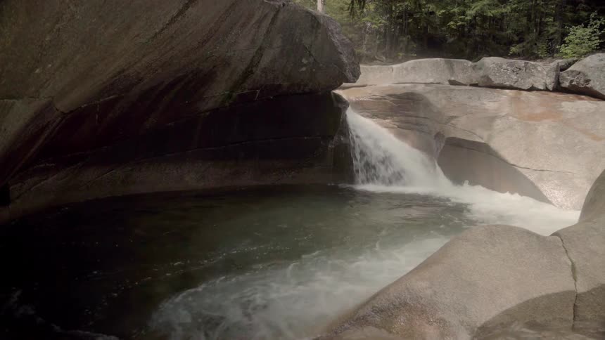 A river flows over rocks and pools between boulders