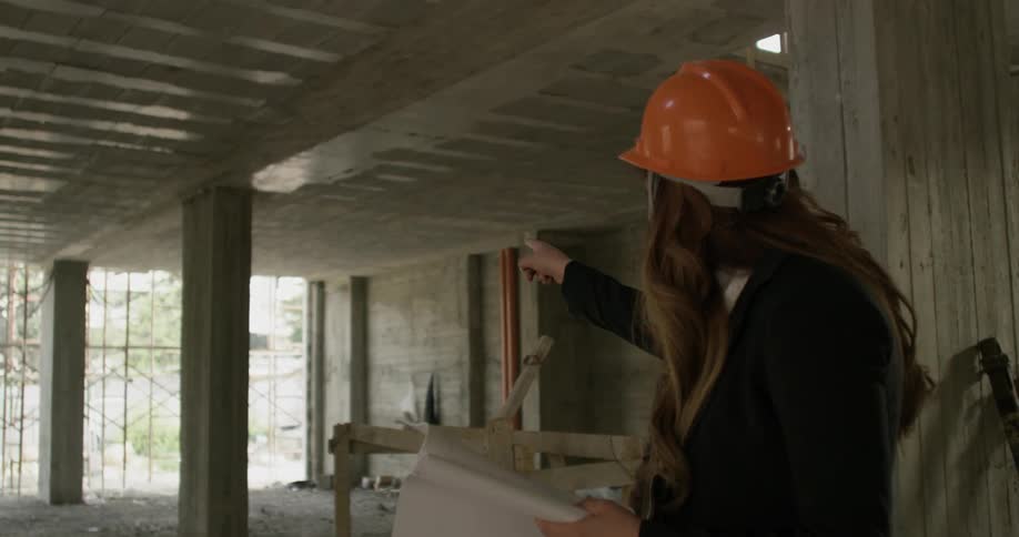 Man and woman look at blueprints at construction site